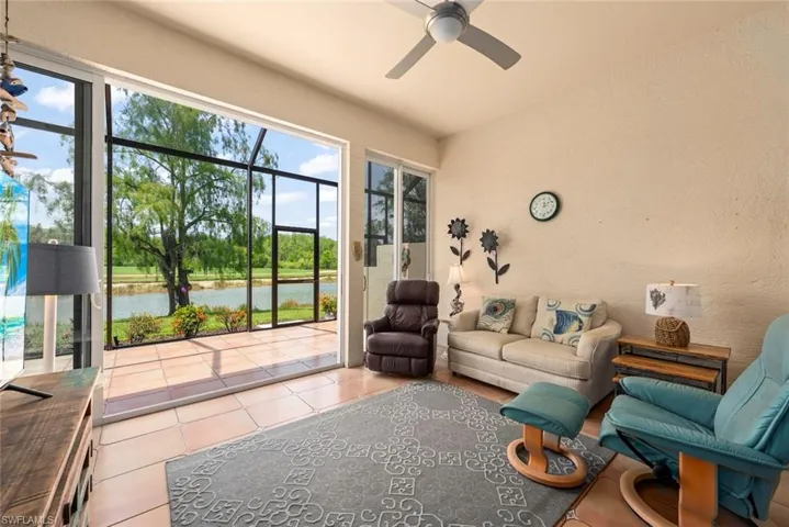 Tiled living room with a water view, a ceiling fan, and a textured wall