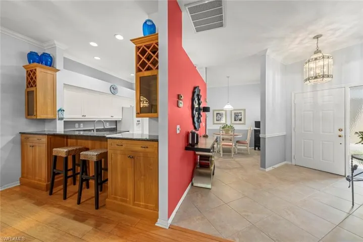 Kitchen with crown molding, baseboards, a breakfast bar, a chandelier, and recessed lighting