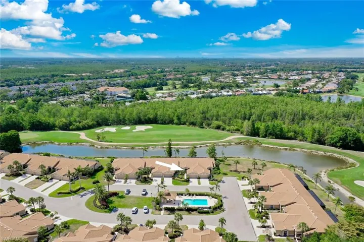 Aerial perspective of suburban area with a nearby body of water, a golf club, and a tree filled landscape