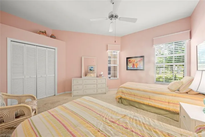 Carpeted bedroom featuring multiple windows, a closet, baseboards, and ceiling fan