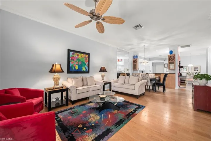 Living room with wood finished floors, a ceiling fan, and crown molding
