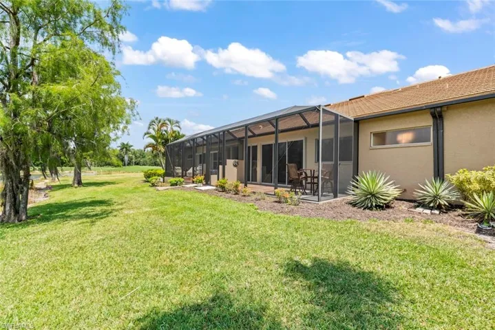 View of grassy yard with a lanai and a patio area