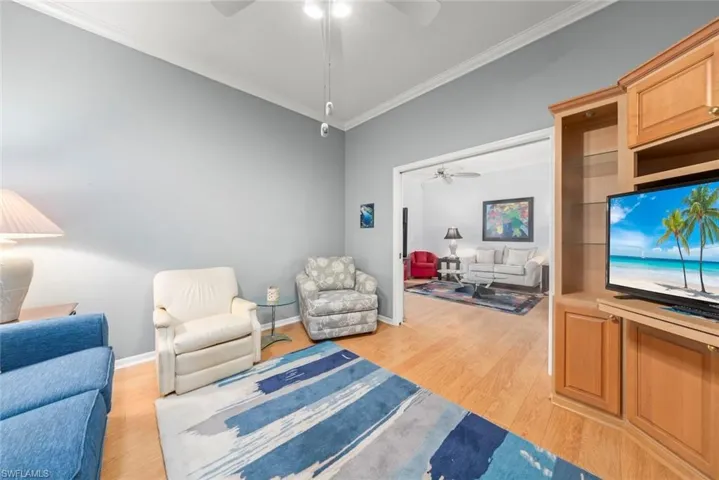 Sitting room with a ceiling fan, ornamental molding, light wood-style flooring, and baseboards