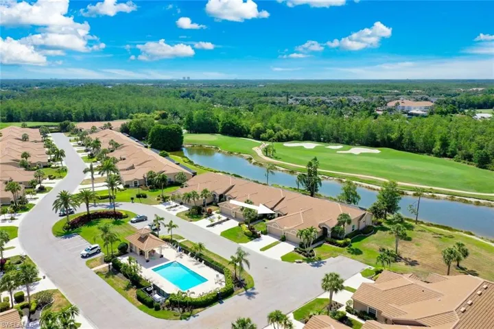Aerial perspective of suburban area with a local golf course, a large body of water, a pool area, and a heavily wooded area