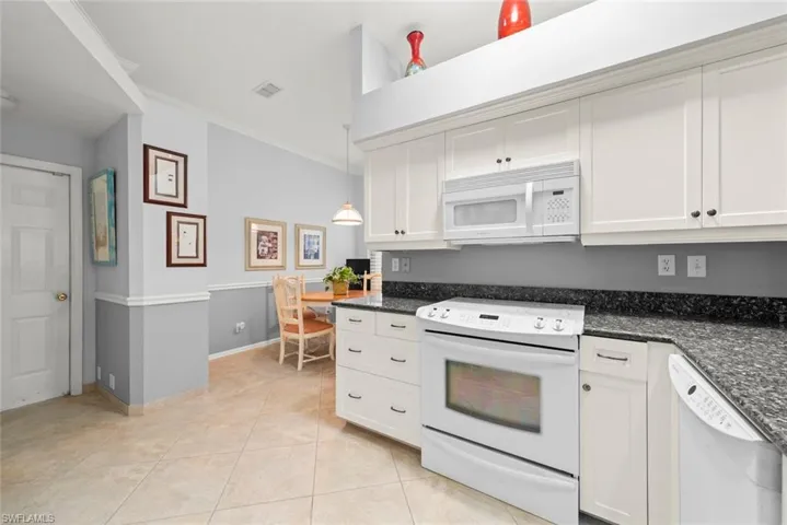Kitchen featuring white appliances, ornamental molding, light tile patterned floors, white cabinets, and baseboards