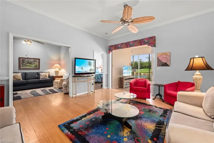 Living room with crown molding, a ceiling fan, and wood finished floors