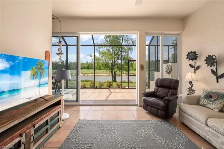 Doorway featuring a water view, light tile patterned floors, a textured wall, and ceiling fan