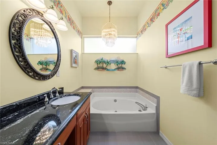 Bathroom with a chandelier, vanity, a bath, and tile patterned floors