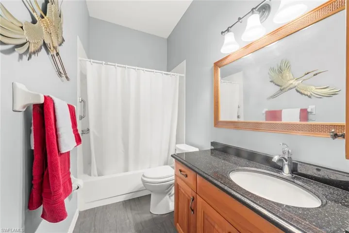 Bathroom featuring vanity, toilet, wood finished floors, and shower / bath combo