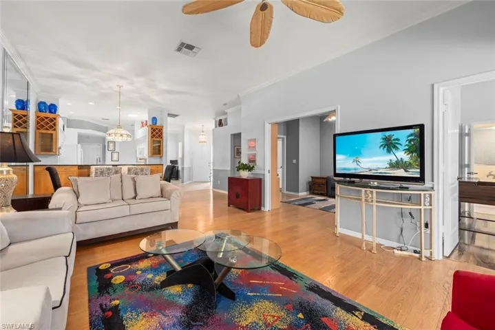 Living area featuring wood finished floors, ceiling fan, and ornamental molding