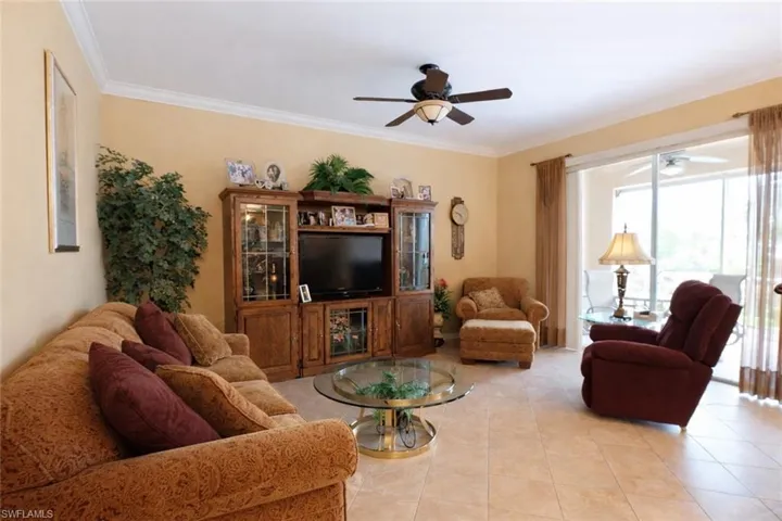 Living room with ceiling fan, ornamental molding, and light tile patterned floors