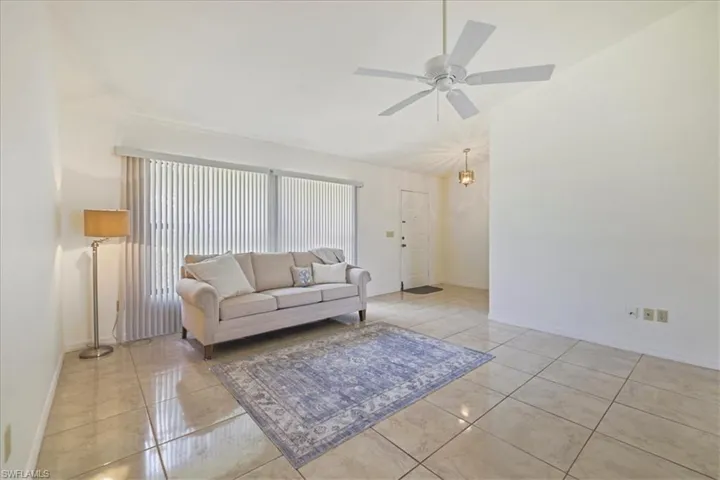 Living area with ceiling fan, baseboards, lofted ceiling, and light tile patterned flooring