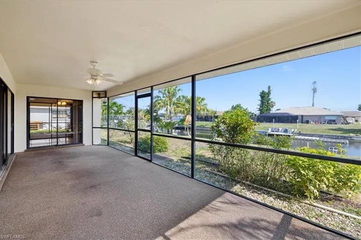 Unfurnished sunroom with ceiling fan, a water view, and a residential view