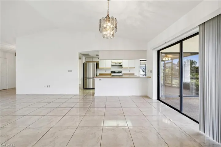 Unfurnished living room featuring vaulted ceiling and a chandelier
