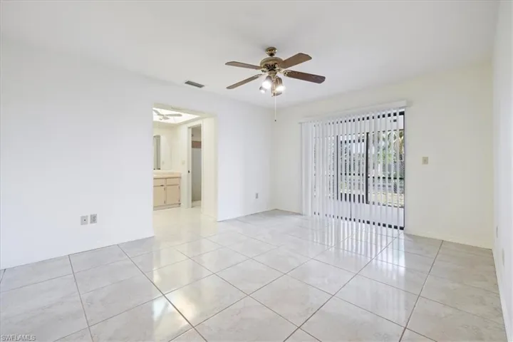 Empty room with light tile patterned floors, ceiling fan, and baseboards