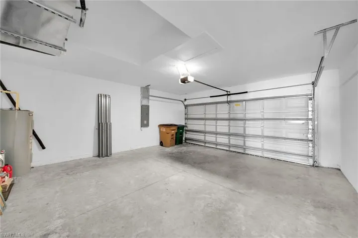 Spacious garage featuring a concrete floor, white walls, and an automatic garage door opener