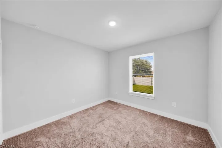 Carpeted room with a single window and recessed lighting