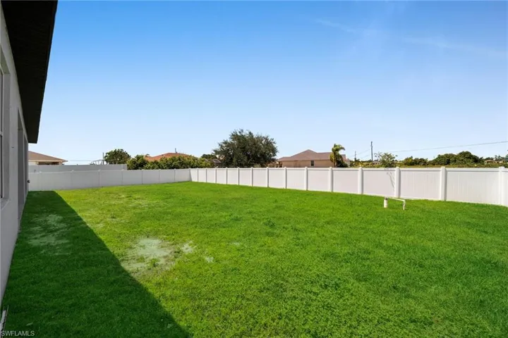 Expansive grass yard with a white privacy fence encompassing the perimeter