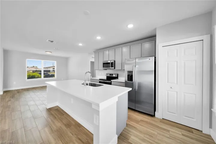 Modern kitchen island featuring a stainless steel sink, gooseneck faucet, and white countertop