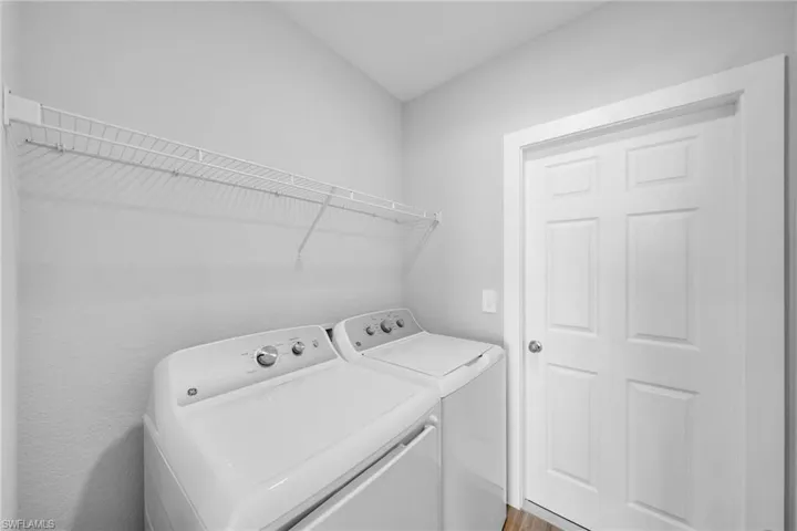 Dedicated laundry area featuring white wire shelving, a six-panel interior door, and light neutral wall paint