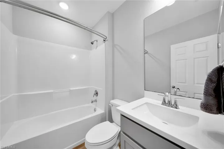 Full bathroom featuring a white tub/shower combination, a vanity with an integrated white sink, a chrome faucet, and a large wall-mounted mirror