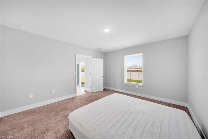Neutral-toned room featuring a single window, white trim, and a warm brown carpet