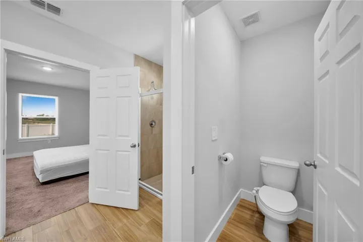 Neutral color palette throughout, featuring light gray walls and wood-finish flooring