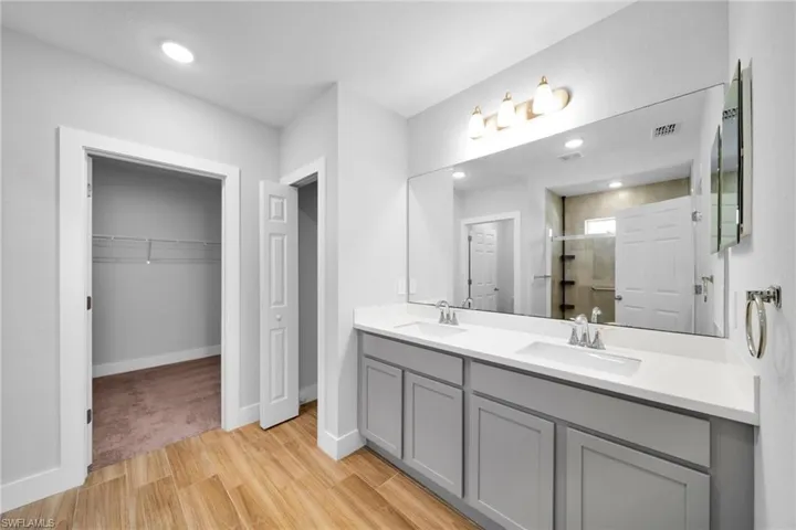 Dual vanity featuring grey cabinetry with white countertops and undermount sinks