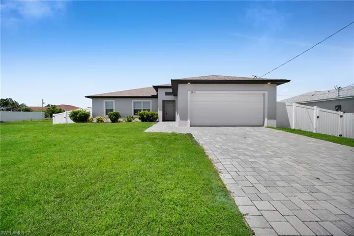 Contemporary single-story residence featuring a two-car garage, paver driveway, and a light gray stucco exterior