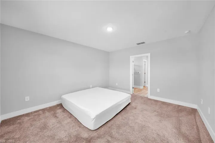 Carpeted interior space featuring light gray walls, white baseboards, and a white ceiling with a recessed light fixture