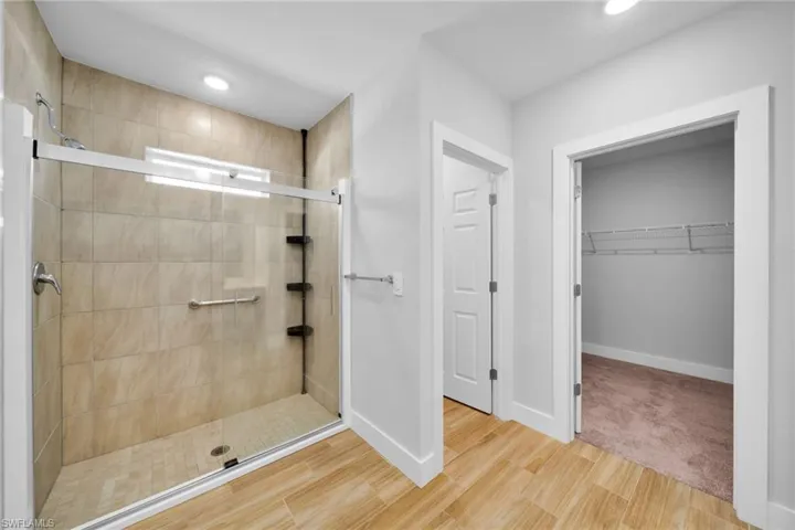 Spacious walk-in shower featuring light-toned tile surround and a clear glass enclosure