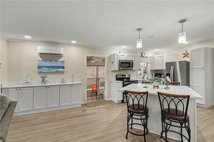 Spacious kitchen featuring an island with seating, white cabinetry, stainless steel appliances