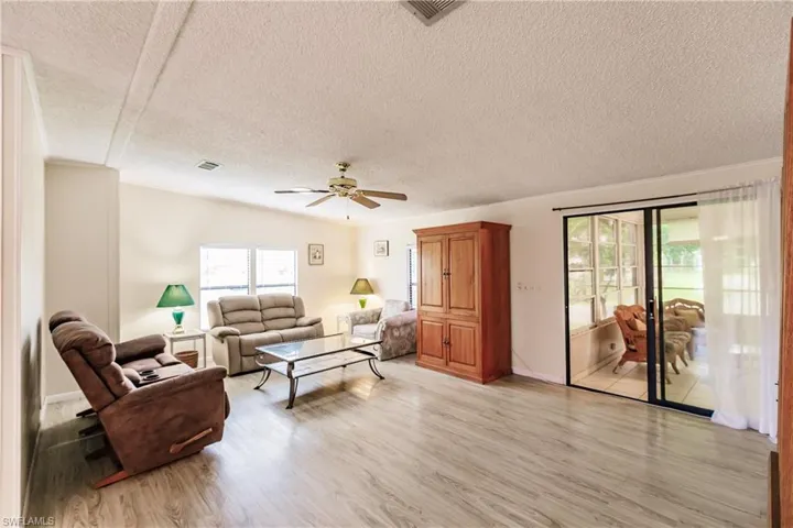 Living room featuring light hardwood / wood-style flooring, a textured ceiling, and ceiling fan