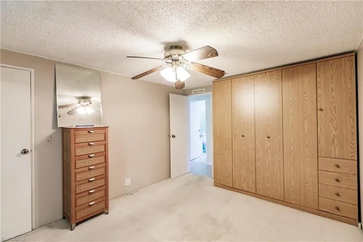 Unfurnished bedroom featuring light carpet, a textured ceiling, and ceiling fan