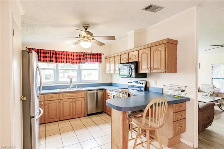 Kitchen with ceiling fan, stainless steel appliances, a wealth of natural light, and kitchen peninsula