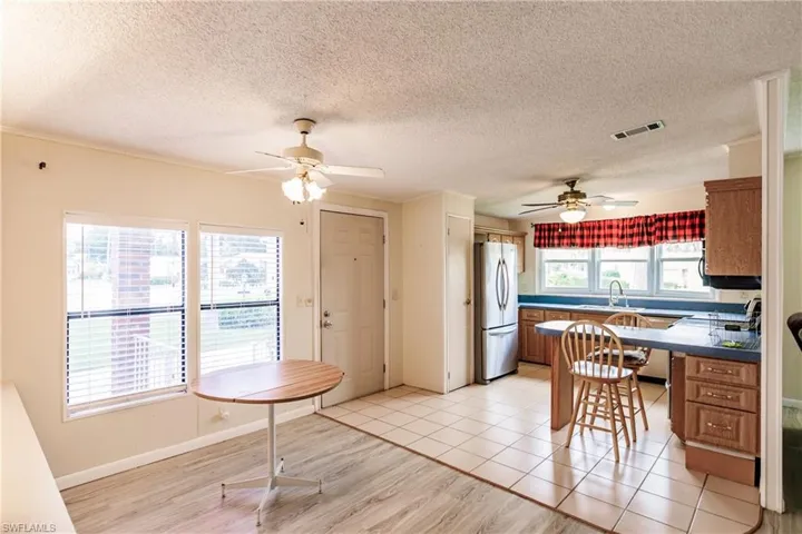 Kitchen with stainless steel fridge, a textured ceiling, light tile patterned floors, and ceiling fan