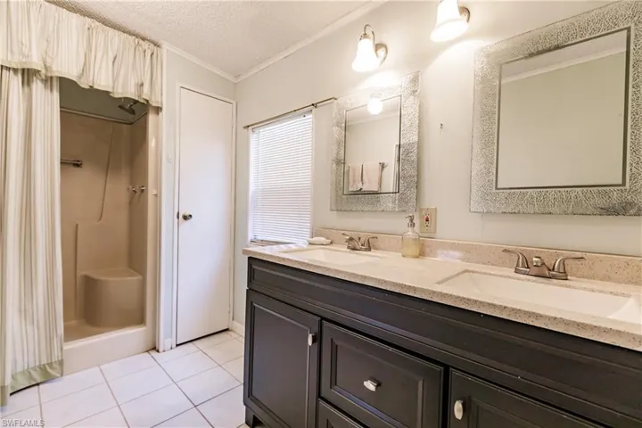 Bathroom featuring ornamental molding, a textured ceiling, tile patterned floors, and double sink vanity