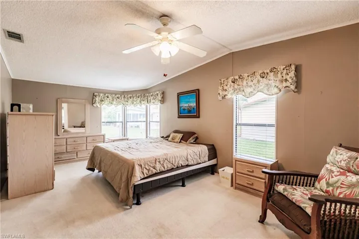 Carpeted bedroom with lofted ceiling, a textured ceiling, and ceiling fan