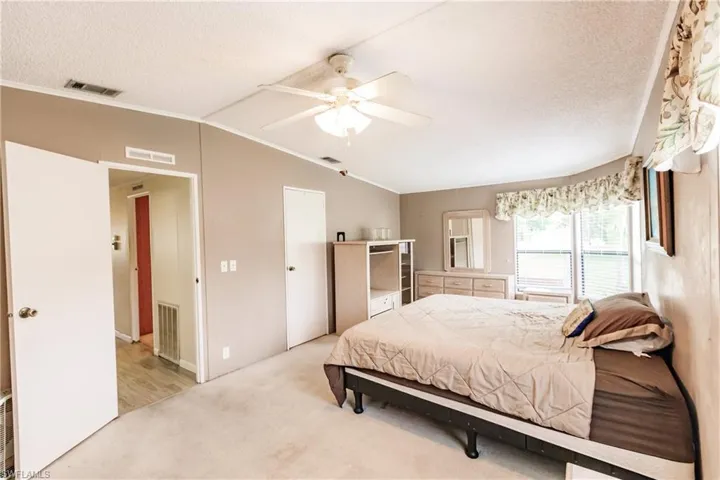 Bedroom featuring lofted ceiling, light carpet, crown molding, and ceiling fan