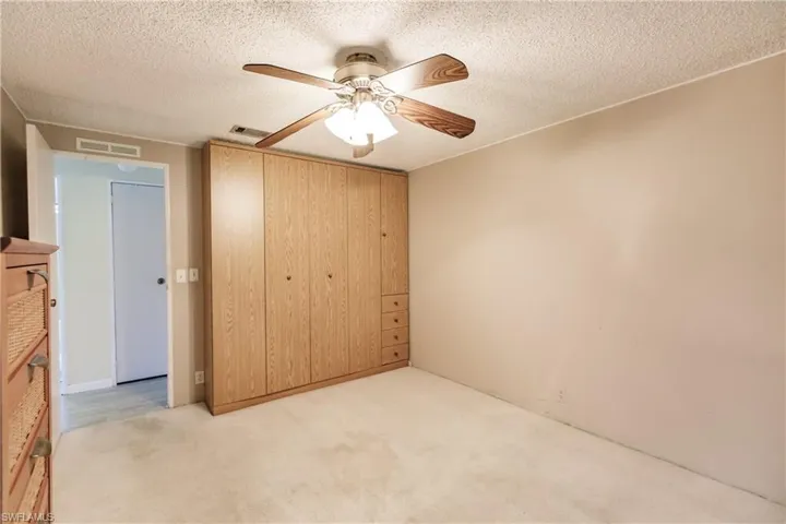 Unfurnished bedroom featuring light carpet, a textured ceiling, ceiling fan, and a closet