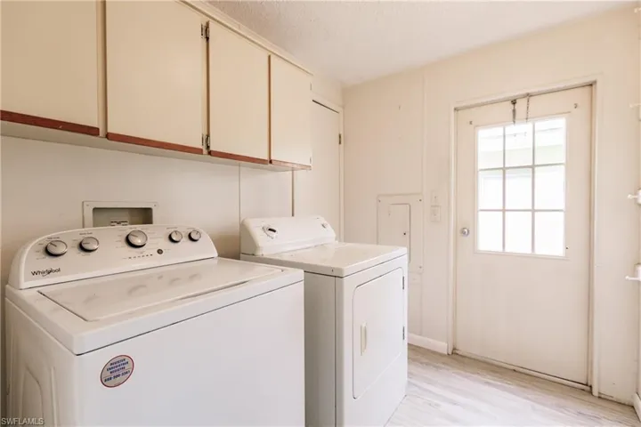 Clothes washing area featuring independent washer and dryer, light hardwood / wood-style floors, and cabinets