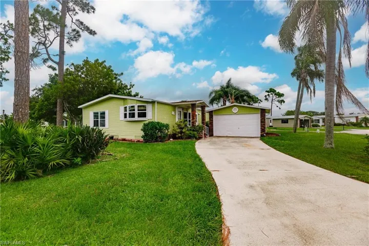 Single story home with a garage and a front lawn