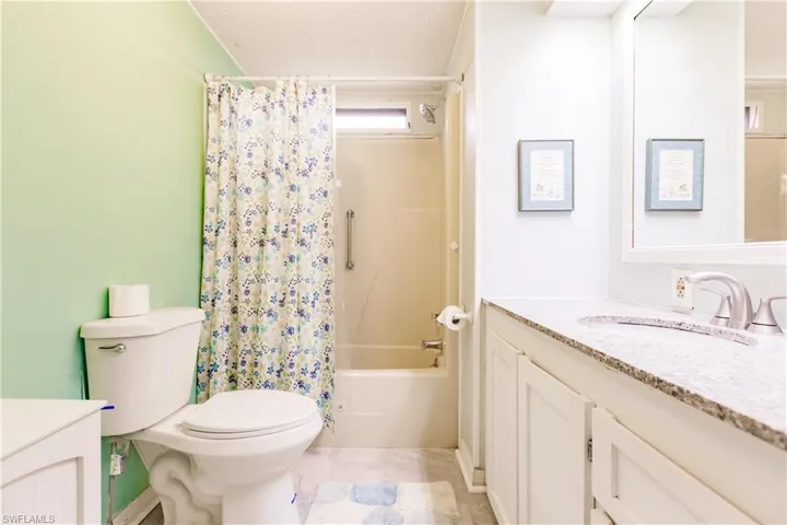 Full bathroom with tile patterned flooring, shower / bath combination with curtain, toilet, and vanity