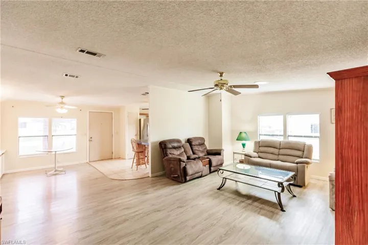 Living room featuring light hardwood / wood-style flooring, a textured ceiling, and ceiling fan