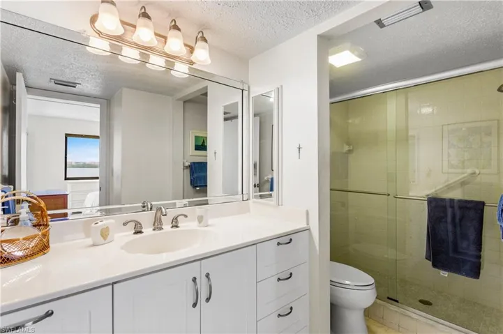 Tall vanity and step in shower with newer heavy glass shower doors.