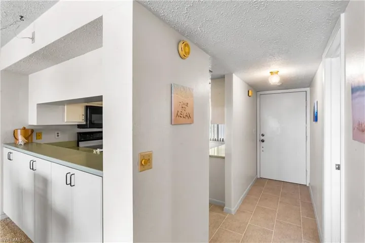 Newer tile in kitchen and foyer, extra cabinetry on back side of counter.