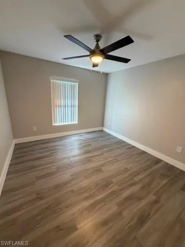 Spacious room featuring wood-finish flooring, neutral-toned walls, and white baseboards