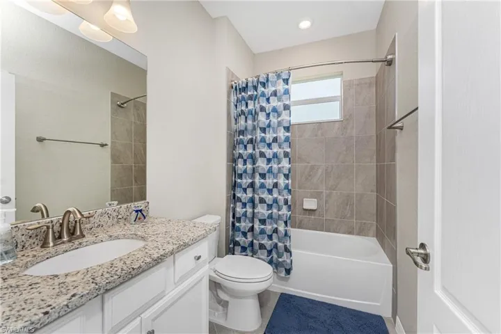 Bathroom featuring vanity, tile patterned flooring, toilet, and shower / tub combo