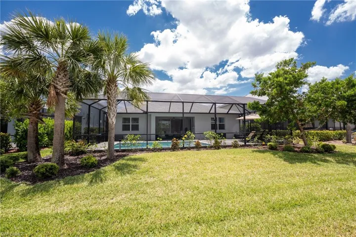 Rear view of house with a lawn, glass enclosure, and an outdoor pool