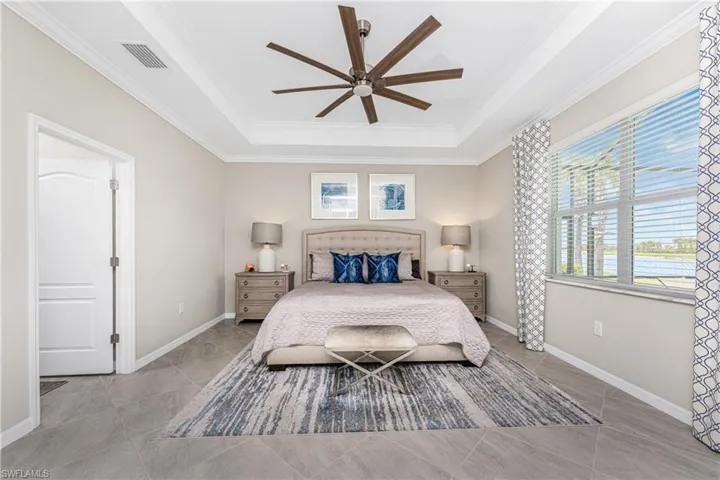 Bedroom featuring crown molding, a raised ceiling, baseboards, and visible vents